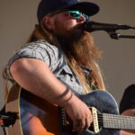 A musican holds a guitar and performs