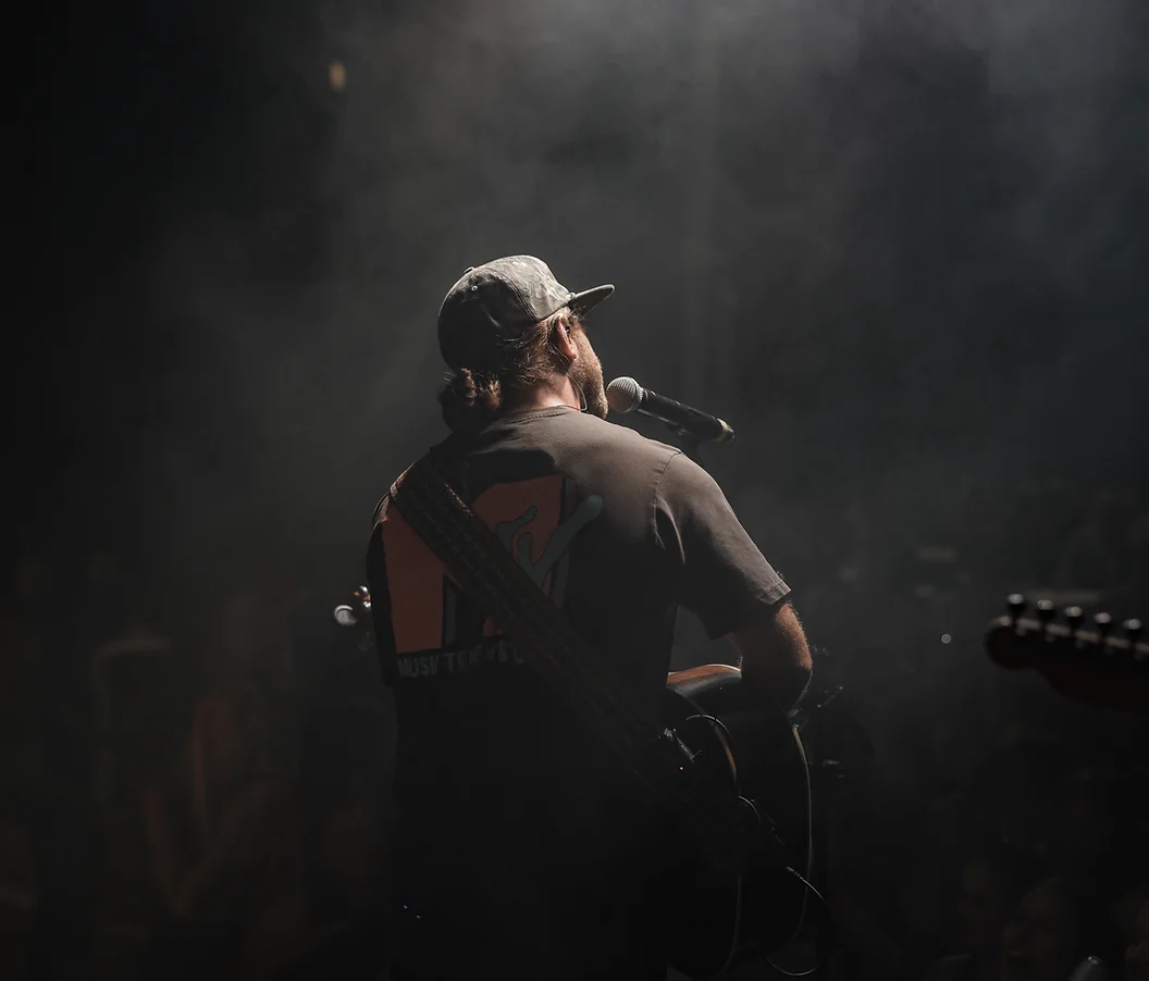 the back of a musician playing guitar on stage
