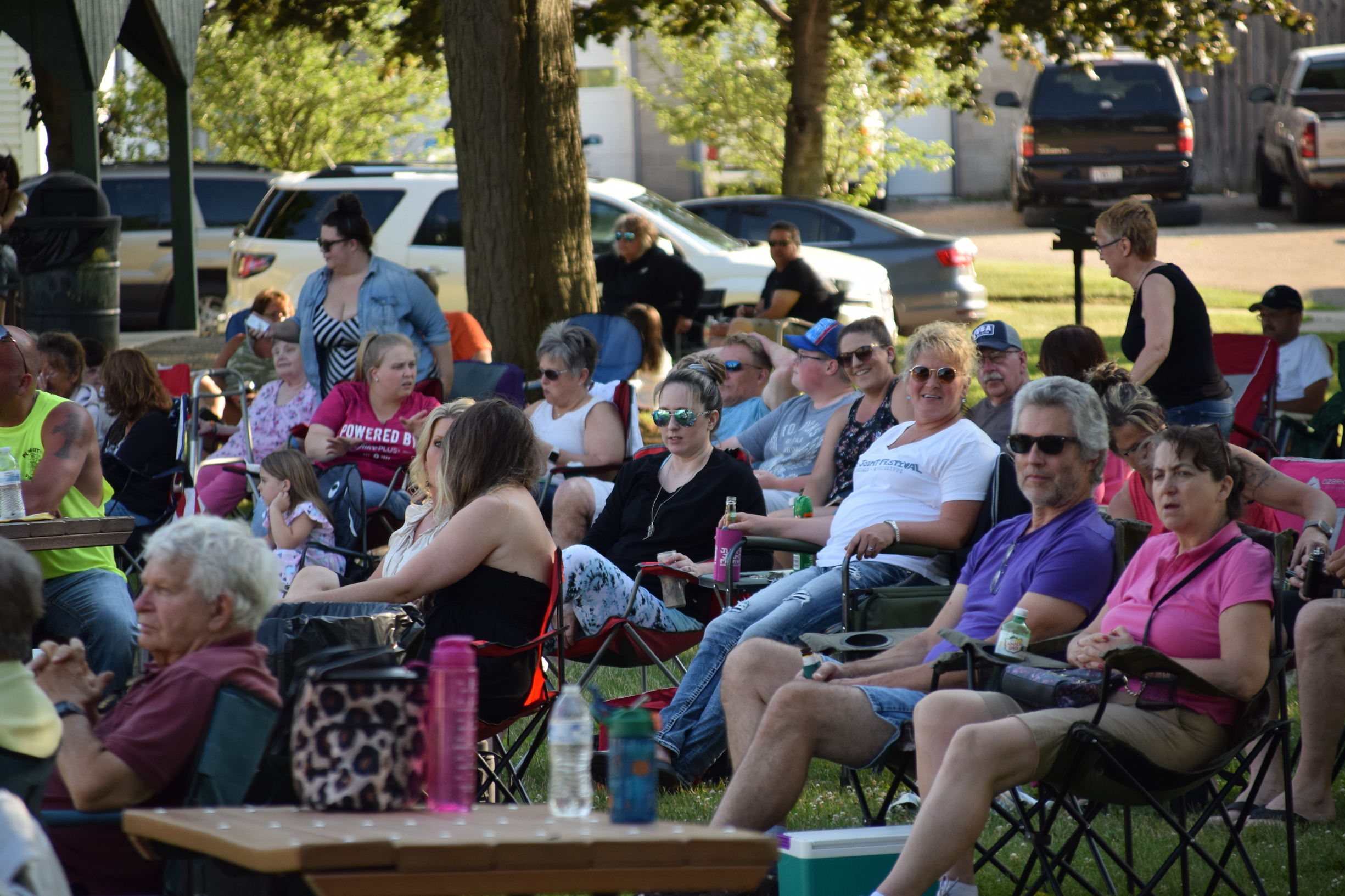 a crowd in lawn chairs listening to live music outdoors