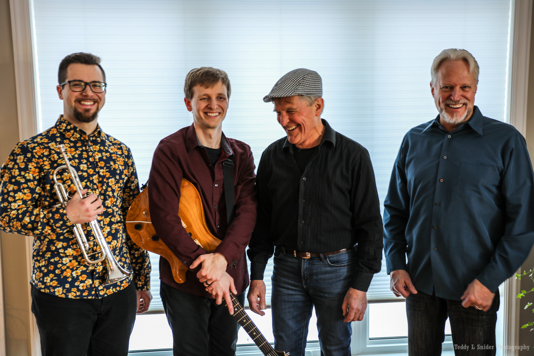 four musicians one holding a guitar and another a trumpet