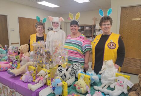 Four people dressed for easter stand in front of easter donations