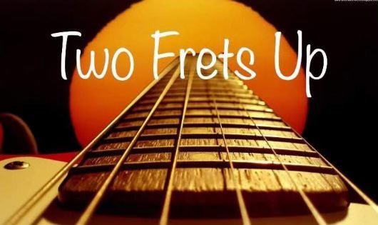 Two Frets Up written over an image of guitar strings.
