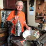 A woman works with metal in her artists shop