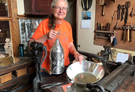 A woman works with metal in her artists shop