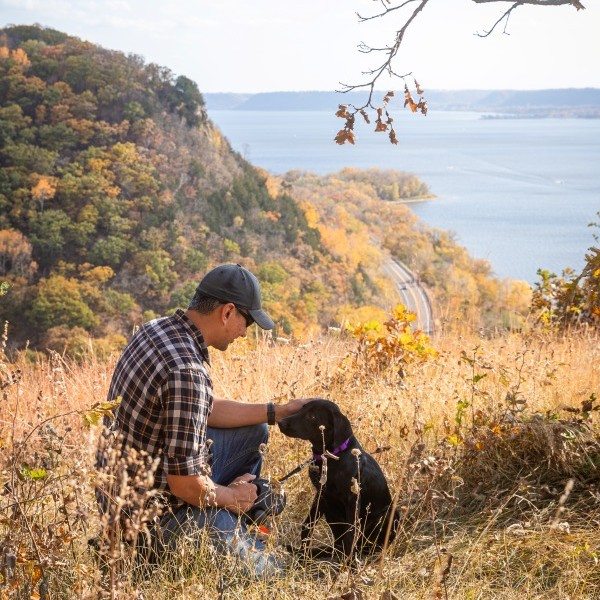 a man and his dog sit atop maiden rock bluff