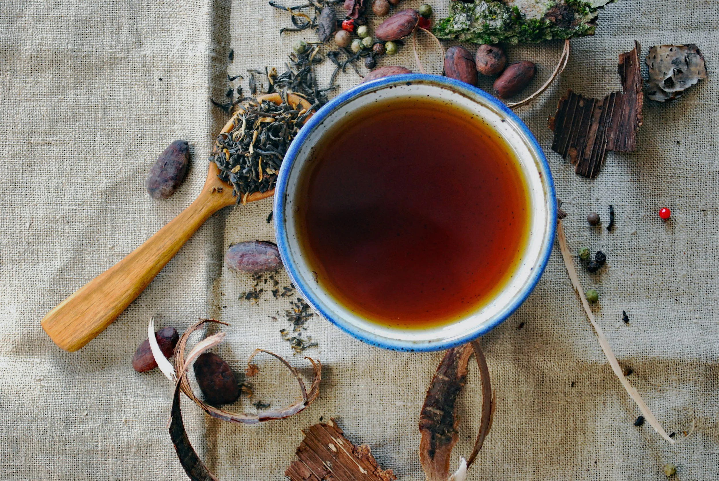 mug of lavender tea with spoon full of dried lavender sitting next to it on a wooden surface