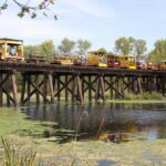 passengers on an open-air train ride on a bridge overlooking the Tiffany Wildlife Area
