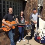 two men and a woman pose with instruments