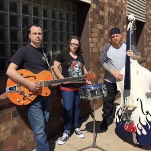 two men and a woman pose with instruments