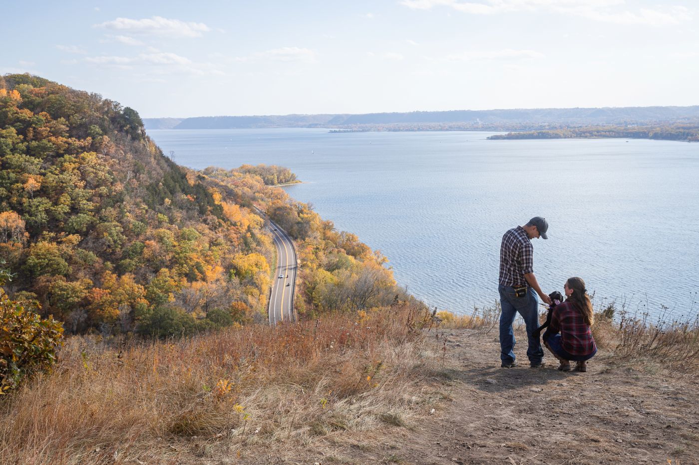 A couple and their dog hike to the edge of Maiden Rock to enjoy the view