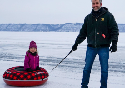 A dad pulls his daughter on a sled on frozen lake pepin.